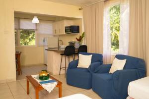 布里奇敦巴巴多斯棕榈园酒店的一间带2把蓝色椅子的客厅和一间厨房
