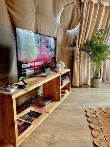 卡齐米日-多尔尼Na Skraju Lasu Domek na Drzewie & Glamping的客厅配有木桌上的平面电视
