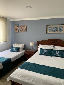 波哥大Hotel Boutique Casa Magaly的酒店客房,设有两张带蓝色墙壁的床