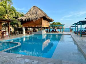 格兰德岛Hotel Isla del Sol的一座带茅草建筑的度假村的游泳池