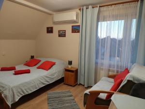 卡齐米日-多尔尼Magnolia Gospodarstwo Agroturystyczne的一间卧室配有两张带红色枕头的床和窗户。