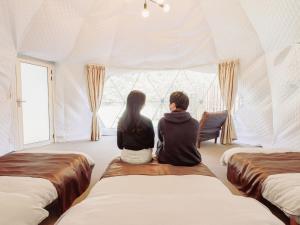 广岛Riverside Glamping Kamiseno - Vacation STAY 92770v的坐在窗外的房间里,男人和女人