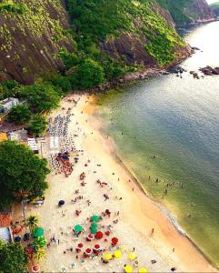 ItaipuPê na areia Loft Praia de Itaipú的海滩上一群人拿着遮阳伞