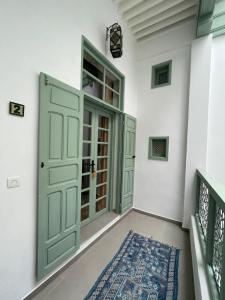 非斯La Maison des Amis的走廊上设有绿门和地毯