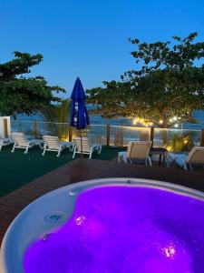 阿拉亚尔达茹达Santorini Beach Hotel的甲板上配有紫色照明的大型热水浴池