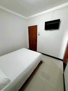 瓦拉达里斯州长市POUSADA BRASÃO的卧室配有一张床,墙上配有电视。