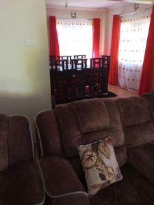 KakamegaAnnex的客厅配有棕色沙发和红色窗帘