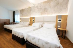 特伦托珠峰酒店的配有白色床单的酒店客房内的两张床