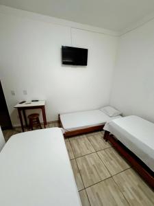 瓦拉达里斯州长市POUSADA BRASÃO的客房设有两张床和一台墙上的电视。