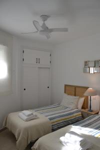 托雷加迪亚罗Beach and Golf House Sotogrande - Torreguadiaro的一间卧室配有两张床和吊扇