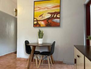 La PlaineA cozy one-bedroom in Heron, Djibouti的一张桌子、两把椅子和墙上的一幅画