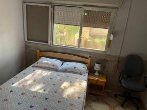 La PlaineA cozy one-bedroom in Heron, Djibouti的一间卧室配有一张床和一把椅子,还有两个窗户