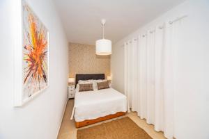 宏达海滩Luxury Apartment Chalana的一间卧室配有床和白色窗帘的墙壁