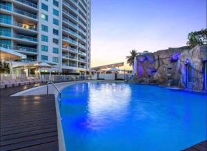 黄金海岸Massive Wings Apartment - 1 Block From Beach的一座大型蓝色游泳池,位于大楼旁边