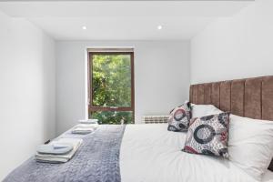 泰晤士河畔金斯顿Elegant Living in Kingston: Two Bedroom Apartment的卧室配有带枕头的床铺和窗户。