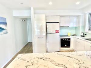 黄金海岸希拉纹假日公寓的厨房配有白色橱柜和冰箱。