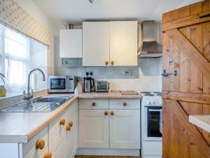 Old BuckenhamButtercup Cottage的厨房配有白色橱柜和木门。