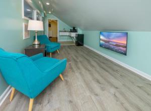 大洋城Commander Beach House Hotel的客厅配有蓝色椅子和平面电视