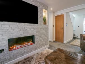 巴罗弗内斯Crag View Cottage的客厅设有壁炉,砖墙上配有电视