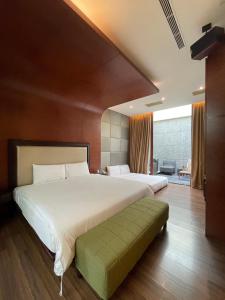 屏东县震点乐汽车商务旅馆的一间卧室配有一张白色大床和绿色长凳