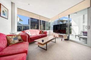 金斯顿Canberra Lakefront 2-Bed with Pool, Gym & Parking的客厅配有2张红色沙发和电视