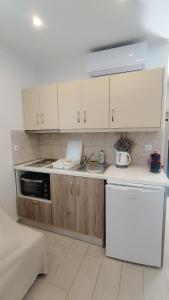 瓦西利基Meltemi Studios的厨房配有白色橱柜、水槽和炉灶。
