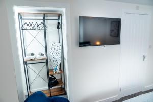 怀特黑Kings Arms Suites - Deluxe Room - En-Suite - Self Check In的客房设有一个衣柜、一台电视和一个架子