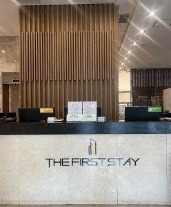 首尔First Stay Hotel的酒店大堂设有柜台,上面有第一张入住标志
