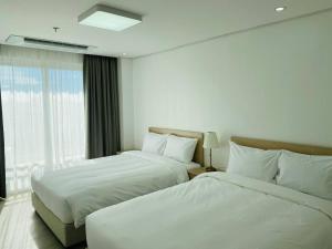MabalacatThe Glory Hotel and Residence的酒店客房设有两张床和窗户。