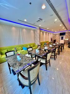 阿吉曼Zenith Smart Vacation Homes, Ajman的餐厅设有桌椅和绿色沙发