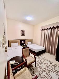 阿吉曼Zenith Smart Vacation Homes, Ajman的酒店客房带两张床和一张桌子以及椅子。
