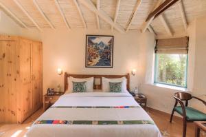 达兰萨拉Tree of Life Birdsong Chalets , Dharamshala的一间卧室设有一张大床和一个窗户。