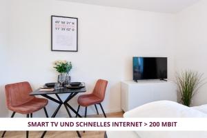 拜罗伊特Apartment Wahnfried No3 - citynah wohnen mit Küche und Duschbad, Parkplatz, 300m zur Fussgängerzone的配有桌椅和电视的客房
