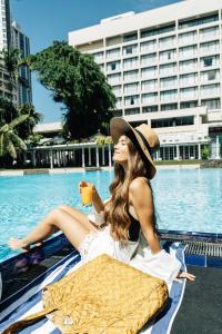 科伦坡肉桂大科伦坡酒店的坐在游泳池旁的戴帽子的女人