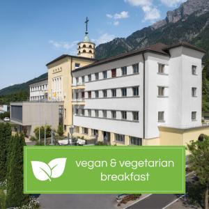 沙恩Kloster by b-smart的一座有绿色标志的建筑,上面写着素食早餐