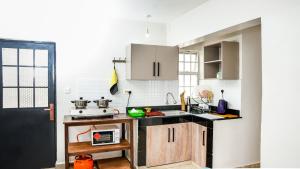 奈瓦沙Kelly homes in Naivasha的厨房配有白色橱柜和黑色台面
