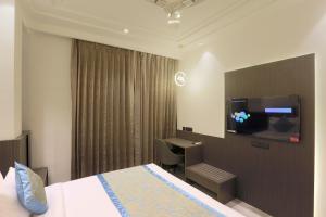 古尔冈OPO Hotel Iffco Chowk的酒店客房设有一张床、一张书桌和一台电视机。