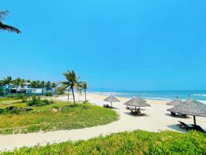 岘港Memories Holiday beach villa Da Nang的海滩上设有遮阳伞和椅子,还有大海