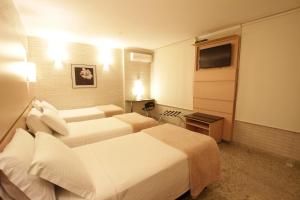 库里提巴Hotel Confiance Centro Cívico的酒店客房设有两张床和电视。