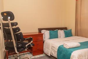 BungomaAriBri Apartment, Bungoma Town.的一间卧室配有一张桌子和一张椅子,位于床边