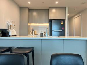 悉尼Sydney Olympic Park View Bliss Modern Design的厨房配有带2把椅子的柜台和冰箱。