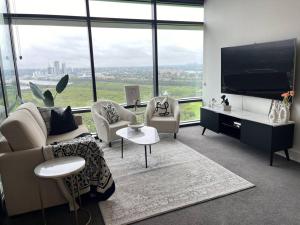 悉尼Sydney Olympic Park View Bliss Modern Design的客厅配有沙发、椅子和电视