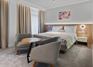 巴尼亚科维利亚查Hotel Podrinje的酒店客房配有一张床、两把椅子和一张桌子