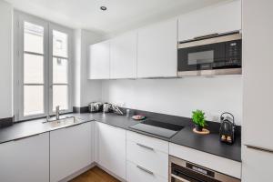 雷恩Appartements Le 31bis的厨房配有白色橱柜和黑色台面