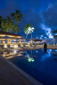 马塞约Jatiuca Hotel & Resort的游泳池,晚上有椅子和棕榈树