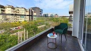 古尔冈AVA Hotels and Corporates Millennium City的阳台配有绿色椅子和桌子