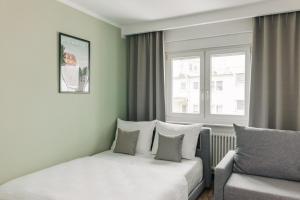 美因河畔法兰克福Homaris Apartments Frankfurt - Digital Check-In的一间卧室配有一张床、一张沙发和一个窗口