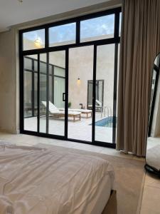 胡富夫شاليهات جزلا的一间卧室设有大窗户,享有游泳池的景色