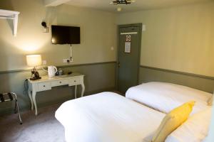 WhittingtonYe Old Boote Inn的酒店客房设有两张床、一张桌子和一台电视。