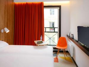 凯恩ibis Styles Caen Centre Historique的酒店客房,配有床和橙色椅子